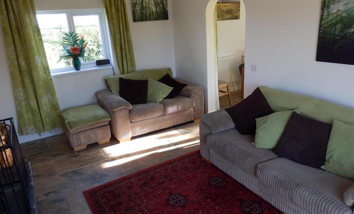 Image shows the arch into the separate kitchen dining area, the comfortable 2 seater sofa and 3 seater sofa bed, the log and multifuel fire (fire guar